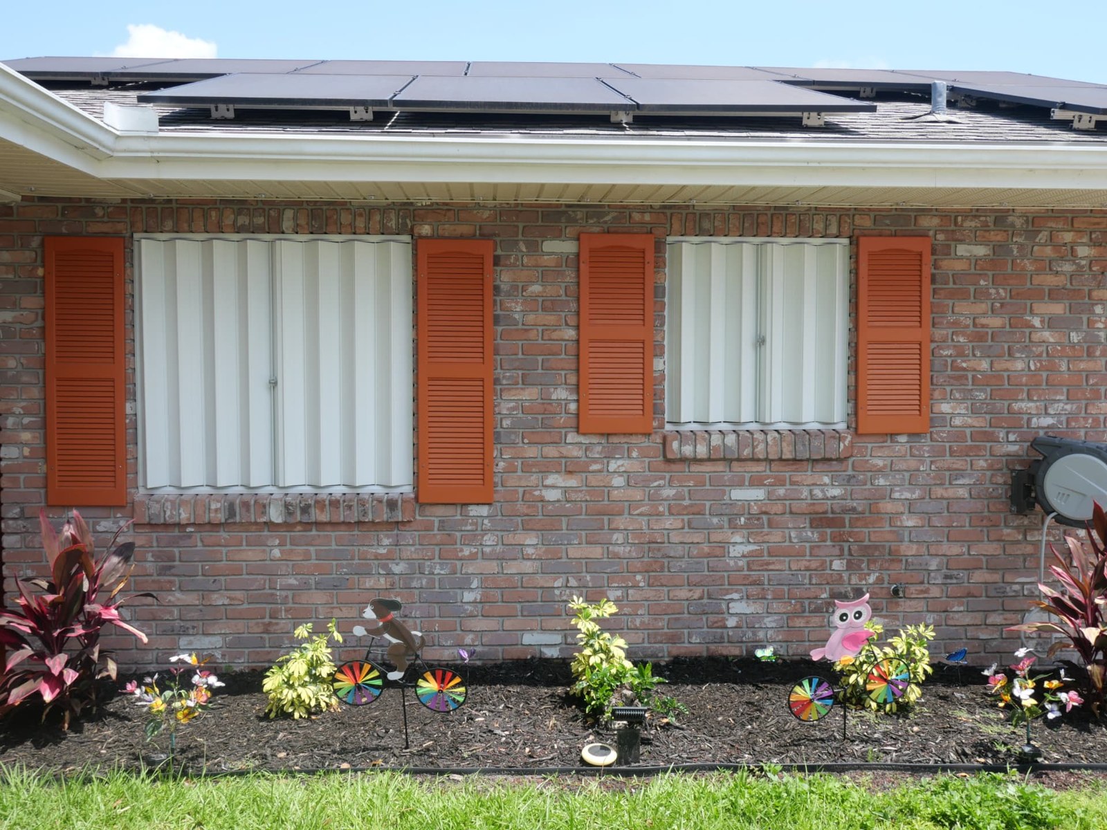 White accordion shutters closed across two brick-home windows