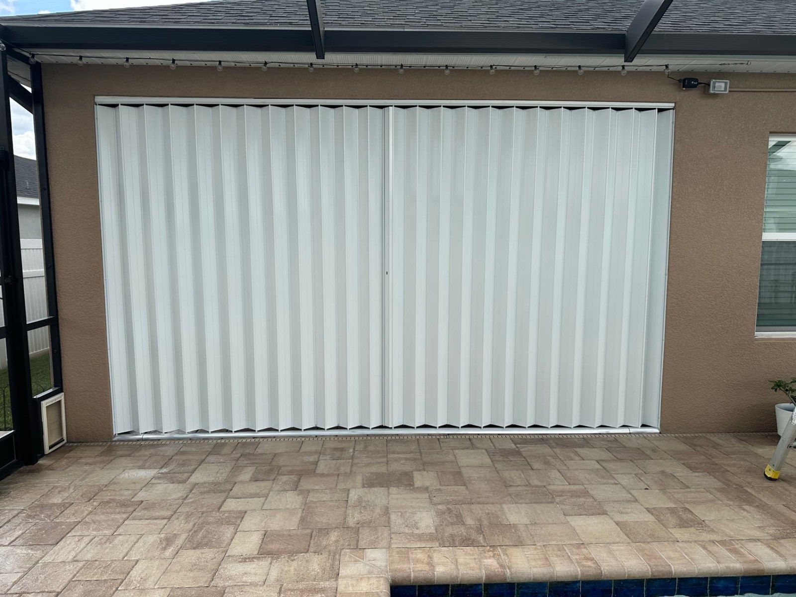 Wide patio opening with white accordion shutters closed